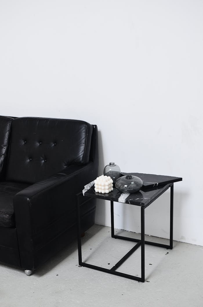 Services-02 Black and white of living room interior with leather sofa near table with decorative candle and vases at home
