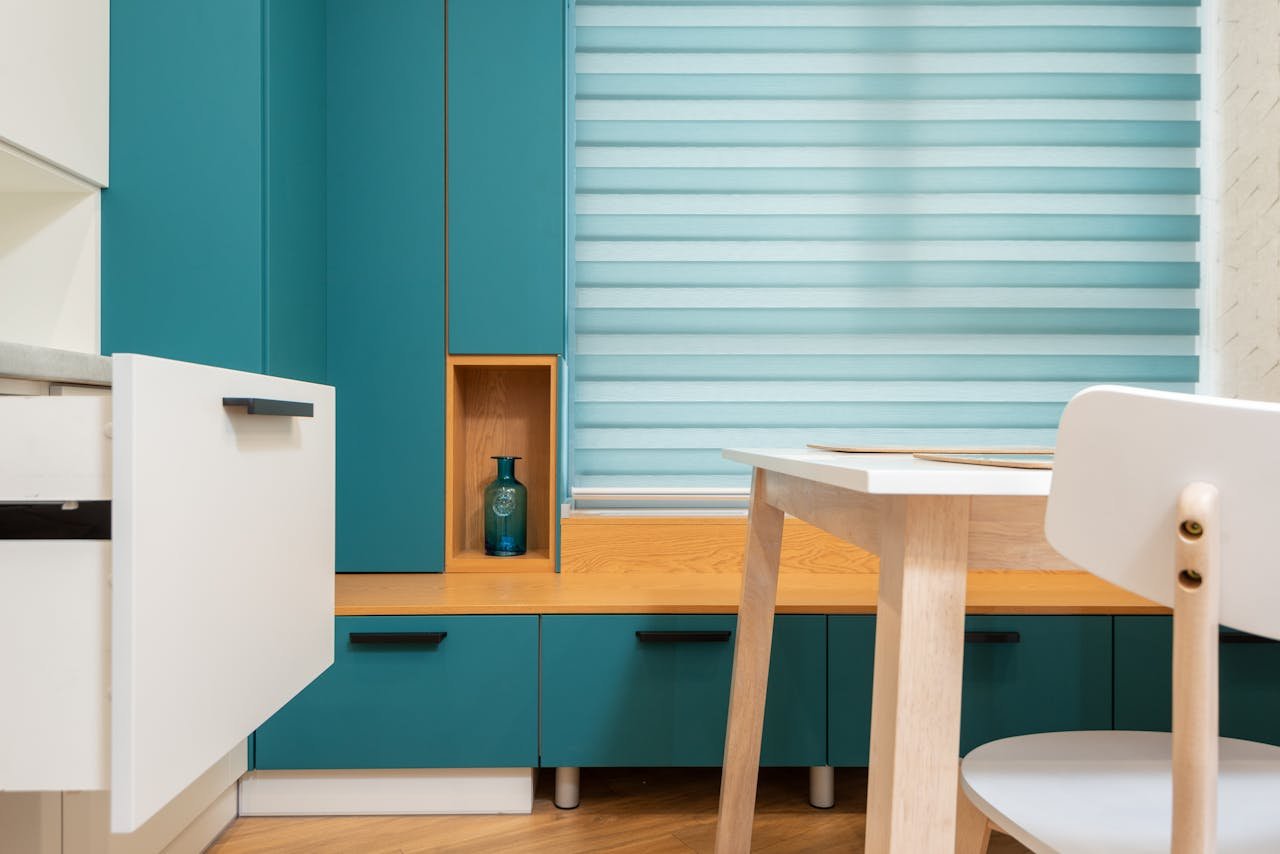 Contemporary kitchen interior featuring teal cabinets and wooden accents for a stylish look.